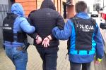 Funkcjonariusze KAS i CBŚP wprowadzają zatrzymanego, ubranego w czarną kurtkę z kapturem, do budynku prokuratury