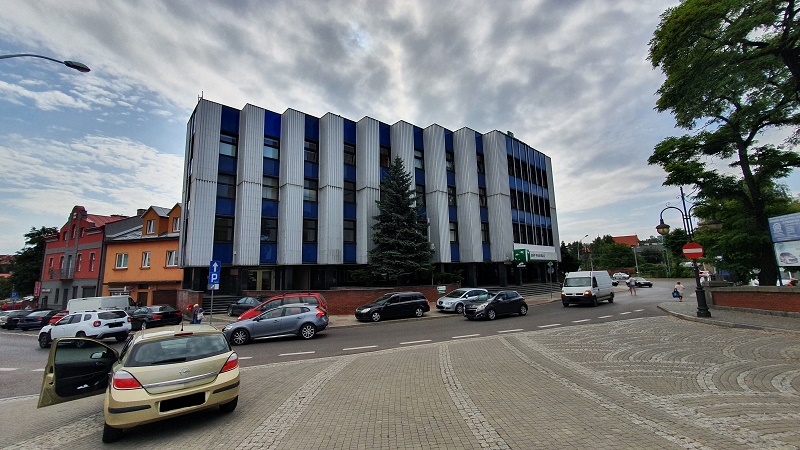 Budynek wielokondygnacyjny. Wejście do budynku dla osób niepełnosprawnych znajduje się po lewej stronie budynku w postaci podjazdu asfaltowego. Po minięciu podjazdu wjeżdża się przez główne wejście do budynku, przy którym znajduje się stanowisko ochrony budynku. 