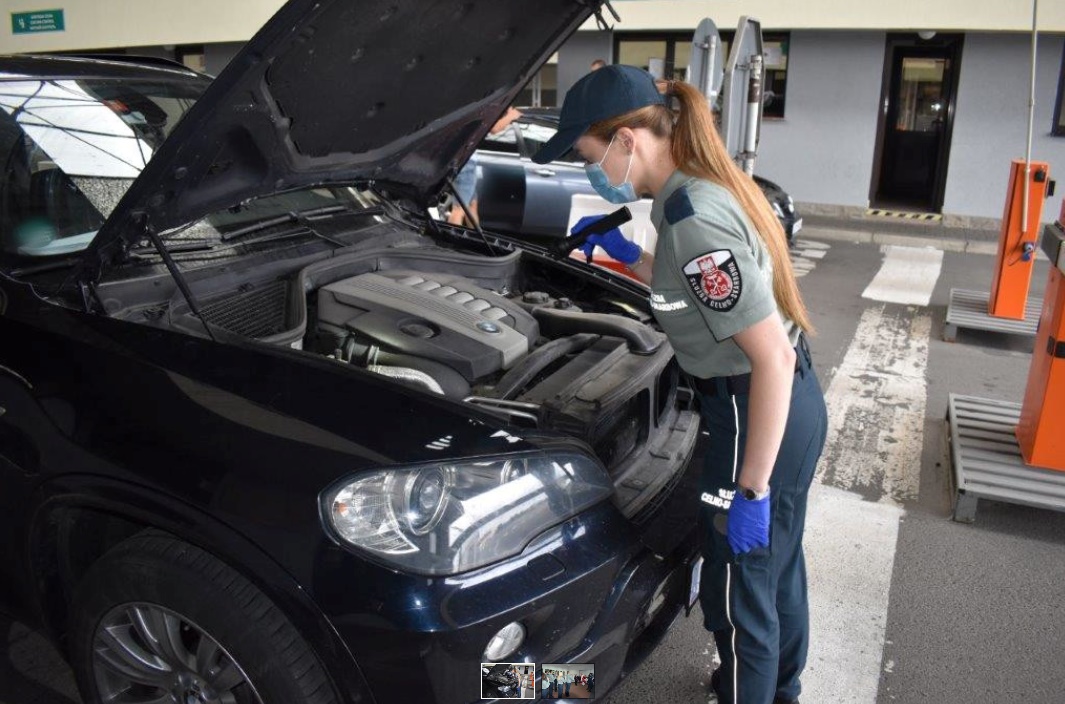 Funkcjonariusz Służby Celno-Skarbowej kontroluje samochód który ma otwartą maskę 