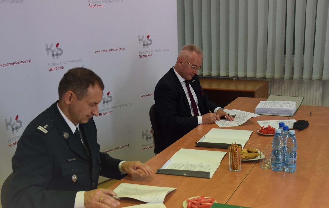 Na zdjeciu Dyrektor IAS w RZeszowie oraz przedstawiciel wykonawcy. Siedzą prze stole i podpisują umowy.