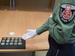 funkcjonariusz Służby Celno- Skarbowej prezentuje wykryte monety