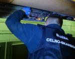 funkcjonariusz Służby Celno- Skarbowej wyjmuje papierosy ze skrytki w autokarze
