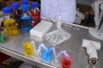 Sprzęt laboratoryjny na metalowym blacie, butelki i zlewki wypełnione są płynami w różnych kolorach