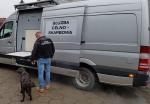funkcjonariusz Służby Celno- Skarbowej z psem Rubi obok mobilnego urządzenia RTG.