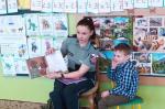 Funkcjonariuszka w przedszkolu pokazuje otwartą książkę, obok siedzi chłopiec