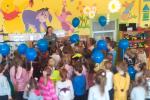 Dzieci w przedszkolu z balonikami, w tle twarzą do nich stoi funkcjonariuszka