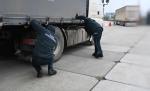 pochyleni funkcjonariusze kontrolują samochód ciężarowy