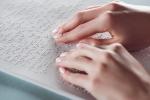 Dłonie na białej kartce zapisanej w alfabecie Braille'a