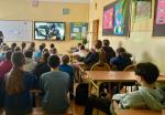 Uczniowie siedzą w sali lekcyjnej i oglądają prezentację 