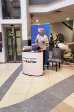 Stoisko informacyjne KSeF. Pracownicy urzędu. Na stoliku ulotki o KSeF