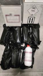 Plastikowa butelka z czerwoną nakrętką leży na z zatrzymanym towarze ofoliowanym czarną folią. 