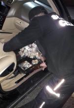 funkcjonariusz wyjmuje z samochodu znalezione papierosy